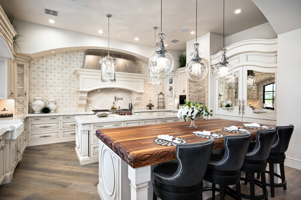 This is an example of a large mediterranean u-shaped kitchen/diner in Phoenix with marble worktops, beige splashback, medium hardwood flooring, multiple islands and a drop ceiling.