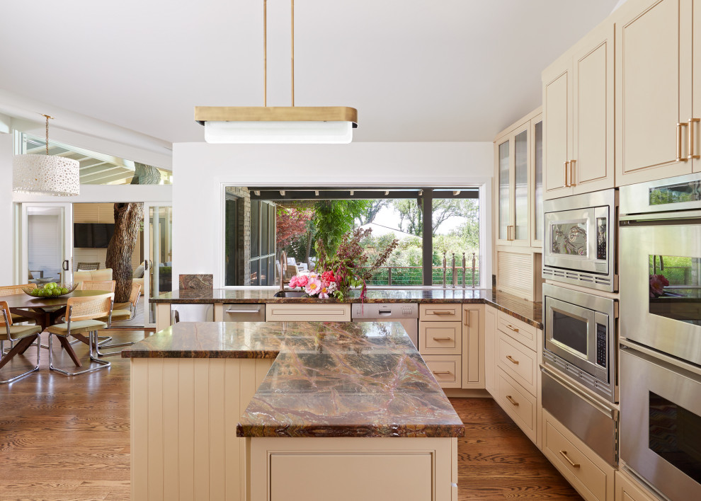 This is an example of a mid-sized transitional l-shaped eat-in kitchen in Austin with a single-bowl sink, recessed-panel cabinets, beige cabinets, marble benchtops, marble splashback, stainless steel appliances, medium hardwood floors, multiple islands, brown floor and purple benchtop.