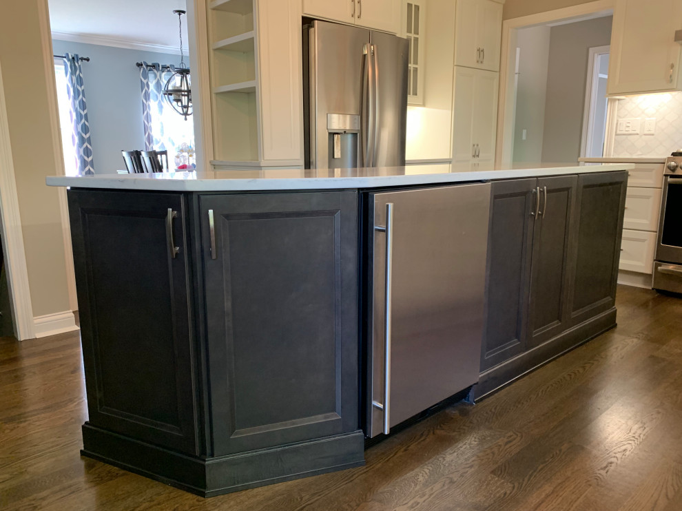 Example of a mid-sized transitional l-shaped medium tone wood floor and brown floor eat-in kitchen design in Cincinnati with an undermount sink, flat-panel cabinets, white cabinets, quartz countertops, white backsplash, marble backsplash, stainless steel appliances, an island and white countertops