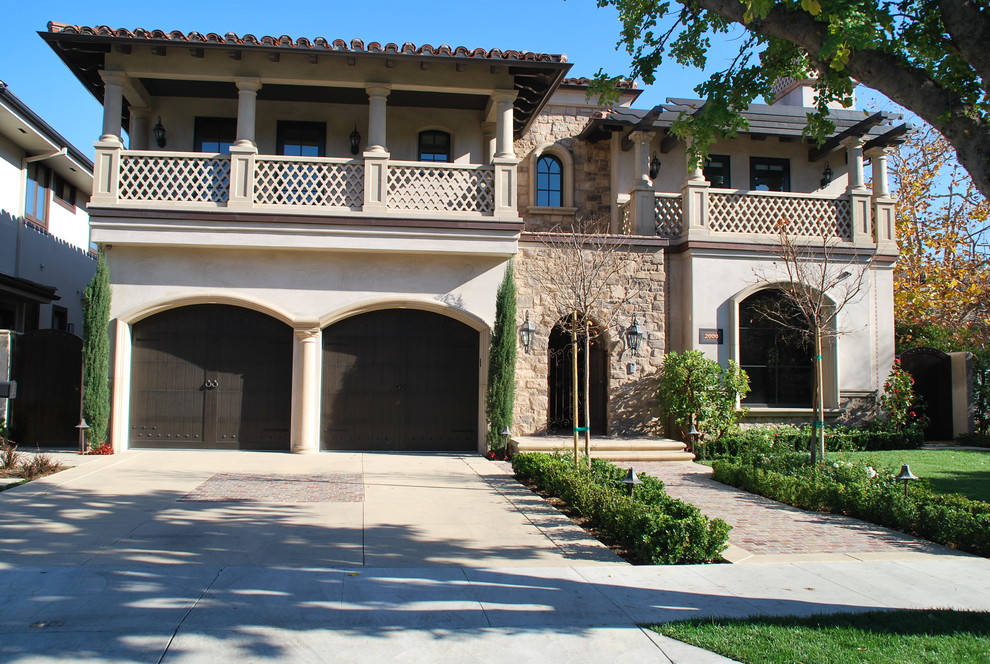 Photo of a mid-sized mediterranean two-storey beige house exterior in Los Angeles with mixed siding, a hip roof and a tile roof.