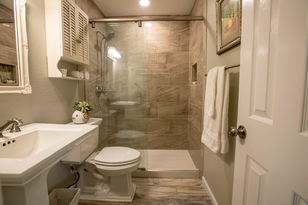This is an example of a small transitional bathroom in Albuquerque with white cabinets, medium hardwood floors, an alcove shower, a one-piece toilet, gray tile, grey walls, a pedestal sink, multi-coloured floor, a sliding shower screen and white benchtops.