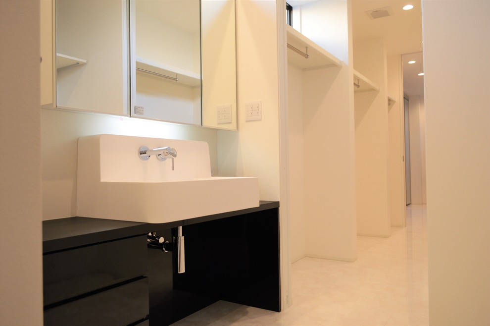 Modern powder room in Other with beaded inset cabinets, black cabinets, white tile, white walls, plywood floors, a drop-in sink, solid surface benchtops, white floor and black benchtops.