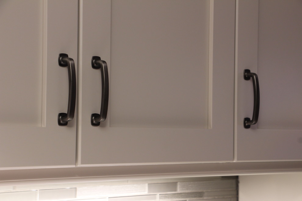 Mid-sized transitional u-shaped ceramic tile and beige floor eat-in kitchen photo in Toronto with a double-bowl sink, shaker cabinets, gray cabinets, solid surface countertops, gray backsplash, glass sheet backsplash, stainless steel appliances and no island