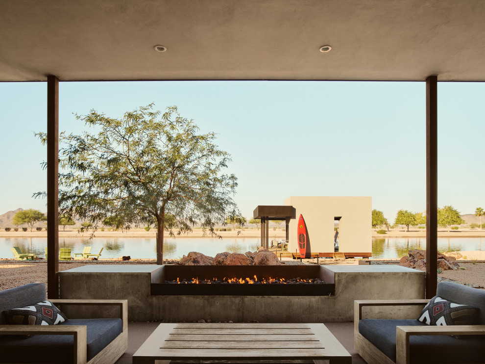 Photo of a back patio in Phoenix with a fire feature, concrete slabs and a roof extension.