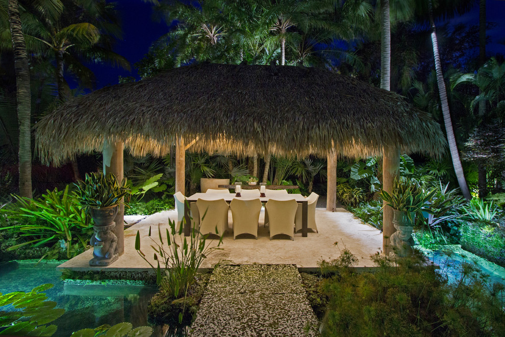 Design ideas for a tropical backyard patio in Miami with a water feature and a gazebo/cabana.
