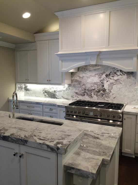 Photo of a transitional kitchen in Cleveland with recessed-panel cabinets, white cabinets, marble benchtops, stone slab splashback and with island.