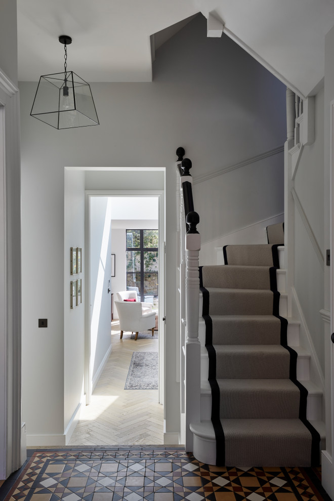 Mid-sized transitional painted curved wood railing staircase photo in London with painted risers