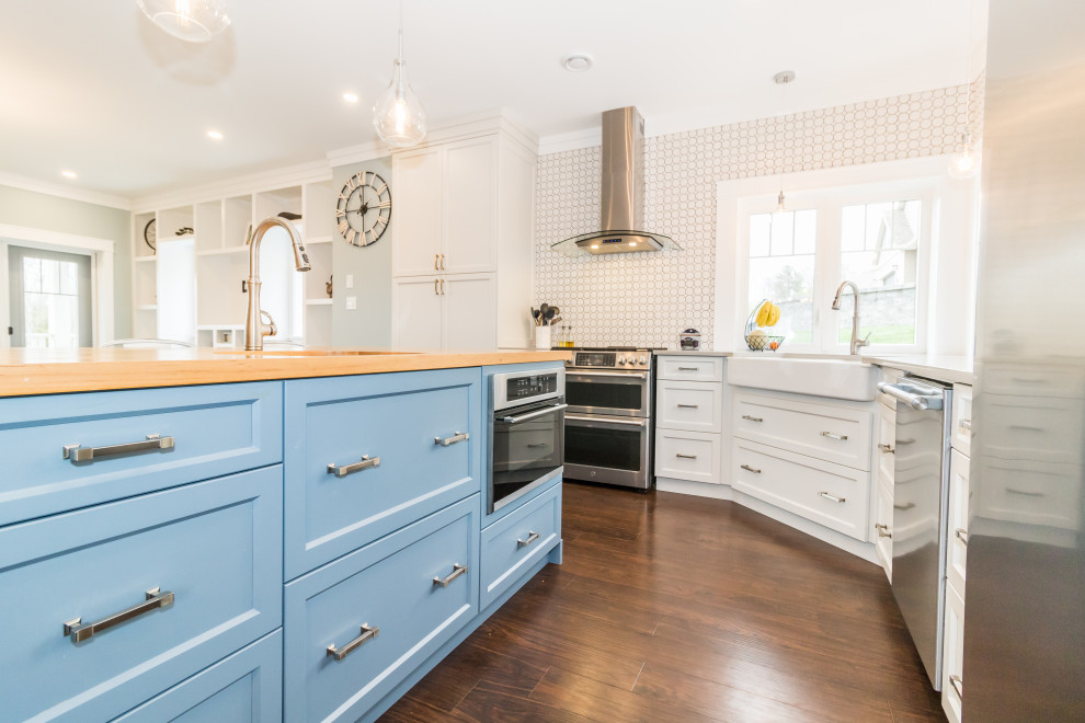 Inspiration for a mid-sized l-shaped vinyl floor and brown floor kitchen remodel with a farmhouse sink, recessed-panel cabinets, multicolored backsplash, ceramic backsplash, stainless steel appliances, an island, gray countertops, blue cabinets and quartzite countertops