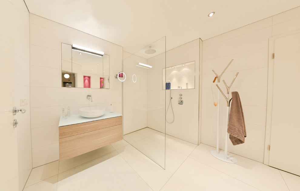 This is an example of a mid-sized modern 3/4 bathroom in Cologne with flat-panel cabinets, brown cabinets, a curbless shower, white tile, stone tile, a vessel sink, solid surface benchtops, beige floor, an open shower, white walls and ceramic floors.