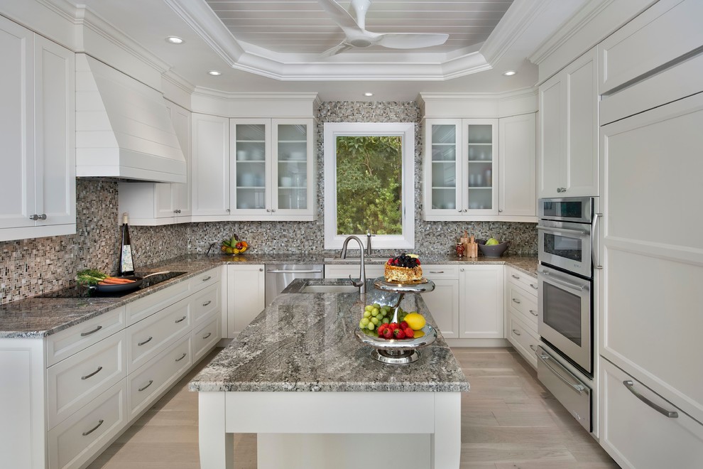Design ideas for a mid-sized transitional l-shaped separate kitchen in Miami with an undermount sink, recessed-panel cabinets, white cabinets, mosaic tile splashback, panelled appliances, light hardwood floors, with island, granite benchtops and grey splashback.