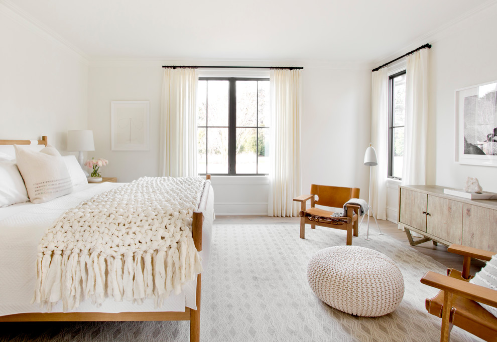 Large scandinavian master bedroom in New York with white walls, light hardwood floors and no fireplace.