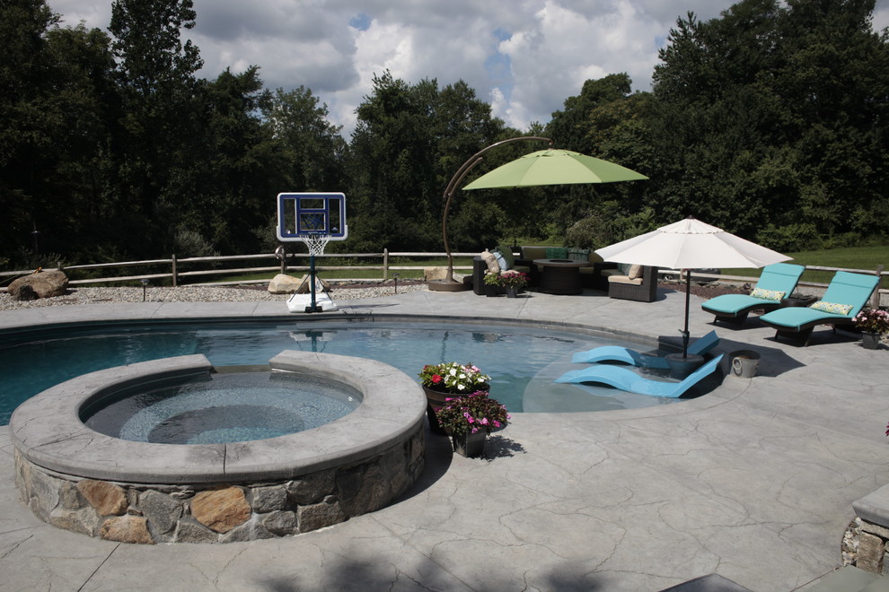 This is an example of a large traditional side yard custom-shaped pool in Bridgeport with a hot tub.
