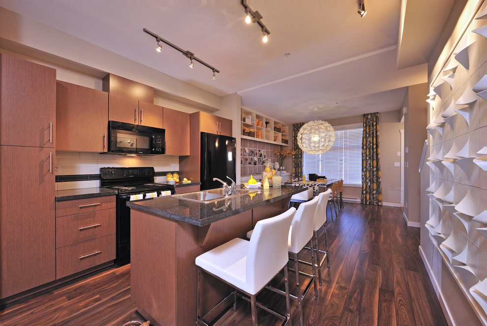 Contemporary galley eat-in kitchen in Vancouver with a drop-in sink, flat-panel cabinets, medium wood cabinets, white splashback and black appliances.