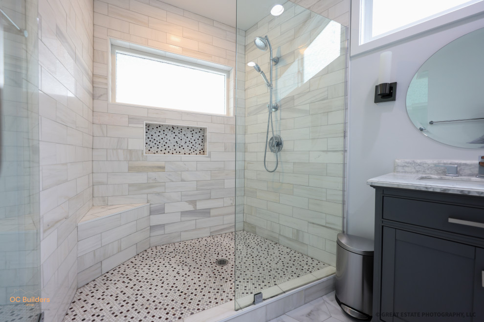 Inspiration for a large modern master bathroom in Orange County with flat-panel cabinets, black cabinets, a freestanding tub, a curbless shower, a one-piece toilet, multi-coloured tile, white walls, porcelain floors, a drop-in sink, marble benchtops, white floor, an open shower, white benchtops, a niche, a double vanity, a floating vanity and vaulted.