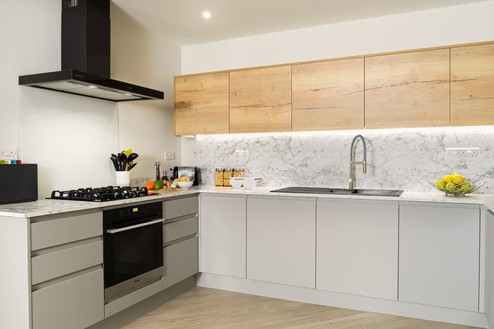 Design ideas for a small contemporary u-shaped separate kitchen in Other with a drop-in sink, flat-panel cabinets, grey cabinets, laminate benchtops, white splashback, glass sheet splashback, black appliances, vinyl floors, no island and white benchtop.