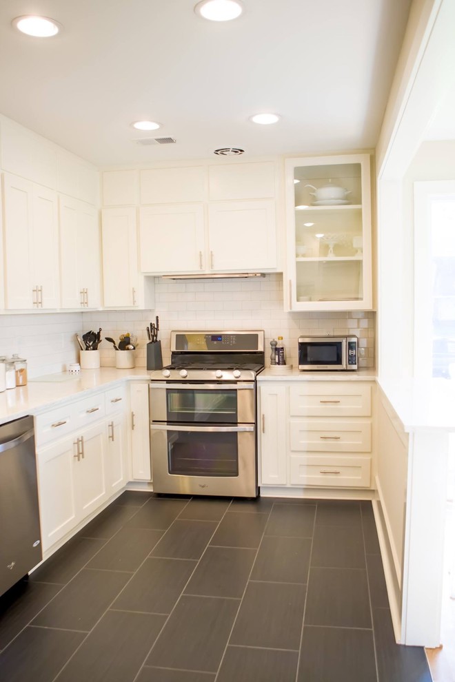 Inspiration for a mid-sized transitional l-shaped eat-in kitchen in Orange County with shaker cabinets, white cabinets, quartz benchtops, white splashback, subway tile splashback, stainless steel appliances, slate floors, no island and black floor.