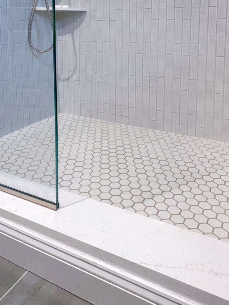 Corner shower - transitional white tile and ceramic tile porcelain tile, gray floor and single-sink corner shower idea in Boston with shaker cabinets, gray cabinets, a one-piece toilet, gray walls, an undermount sink, quartz countertops, a hinged shower door, white countertops and a built-in vanity