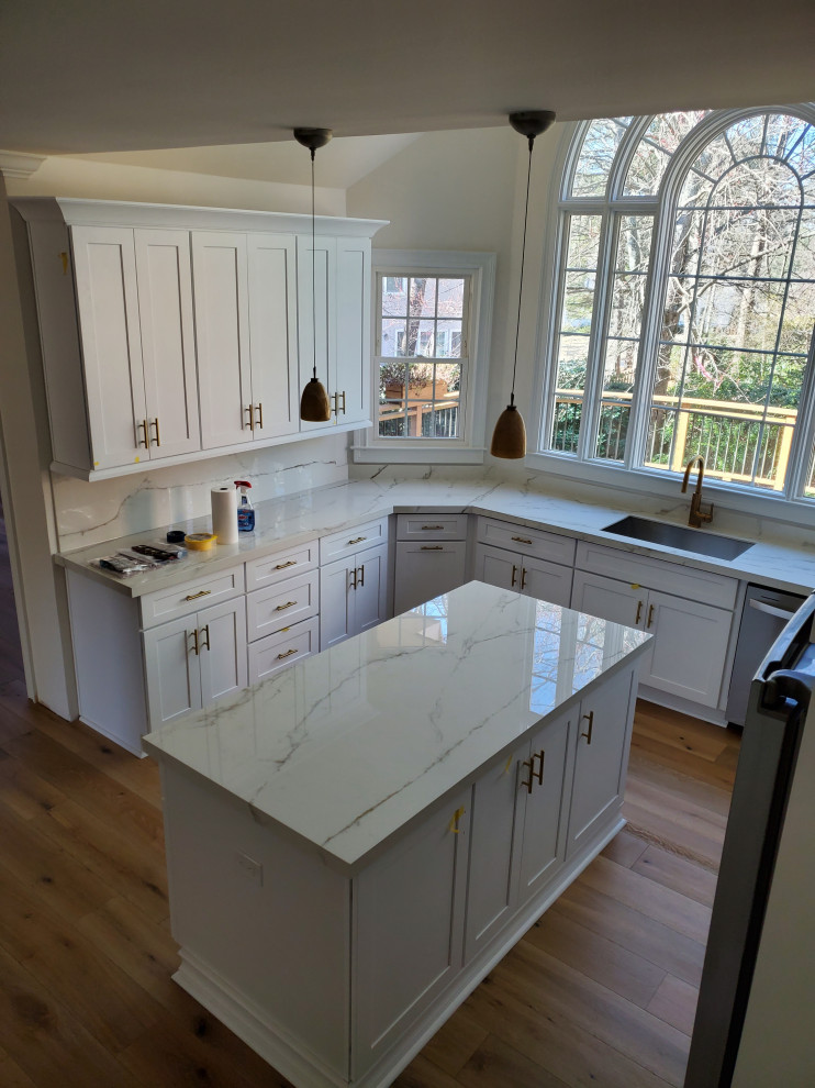 Foto på ett stort funkis kök, med en undermonterad diskho, skåp i shakerstil, vita skåp, stänkskydd i porslinskakel, rostfria vitvaror, mellanmörkt trägolv och en köksö