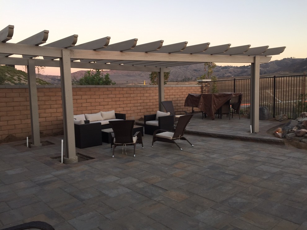 This is an example of a large traditional backyard patio in Orange County with concrete pavers and a pergola.