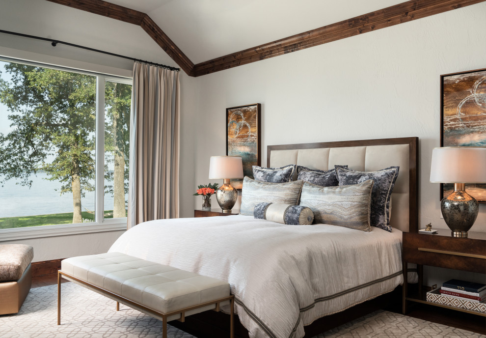 Large mountain style master dark wood floor and brown floor bedroom photo with beige walls