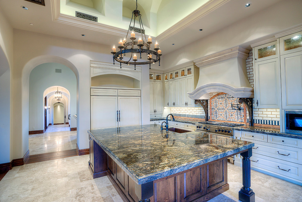 Inspiration for an expansive mediterranean u-shaped eat-in kitchen in Phoenix with a farmhouse sink, recessed-panel cabinets, stainless steel appliances, medium wood cabinets, granite benchtops, beige splashback, mosaic tile splashback, travertine floors and with island.