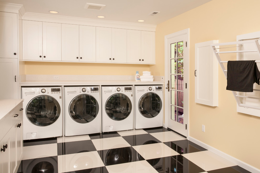 Large traditional l-shaped utility room in Seattle with an undermount sink, shaker cabinets, white cabinets, quartz benchtops, yellow walls, porcelain floors and a side-by-side washer and dryer.