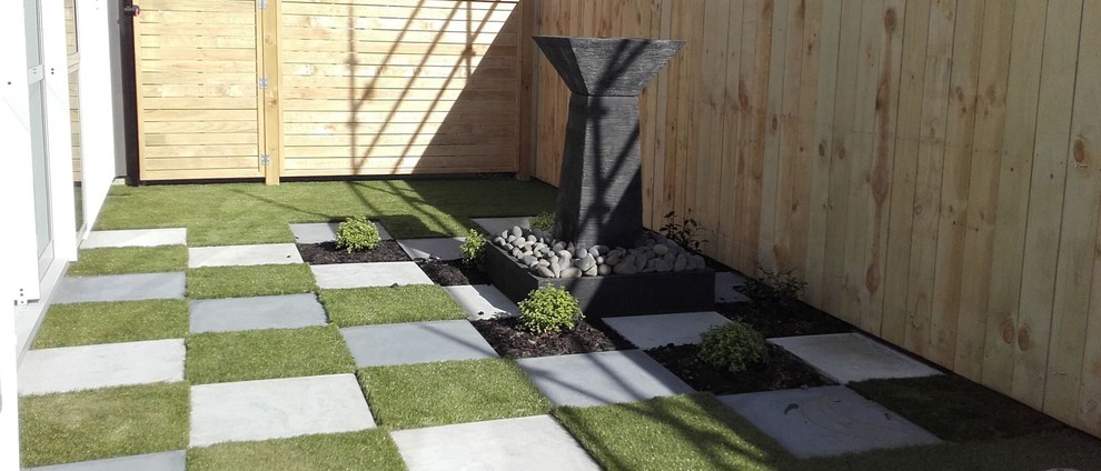 Inspiration for a mid-sized contemporary courtyard partial sun garden for winter in Auckland with concrete pavers.