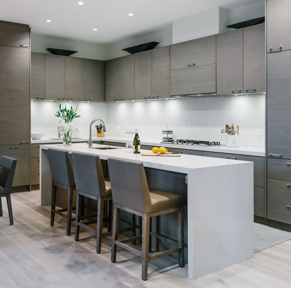 Photo of a large contemporary l-shaped eat-in kitchen in Vancouver with an undermount sink, flat-panel cabinets, dark wood cabinets, quartzite benchtops, white splashback, stone slab splashback, panelled appliances, with island, light hardwood floors and beige floor.