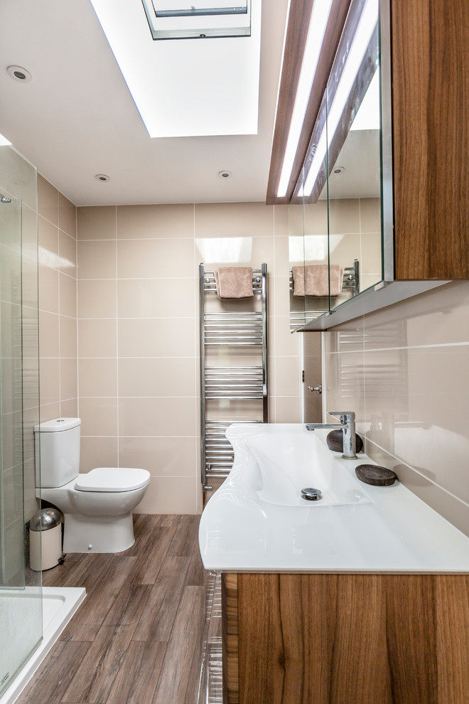 This is an example of a mid-sized contemporary master bathroom in Kent with flat-panel cabinets, dark wood cabinets, a corner shower, a two-piece toilet, cement tile, beige walls, dark hardwood floors, a drop-in sink, brown floor and an open shower.