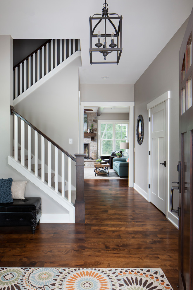 Photo of a mid-sized arts and crafts foyer in Milwaukee with grey walls, dark hardwood floors, a single front door, a dark wood front door and brown floor.