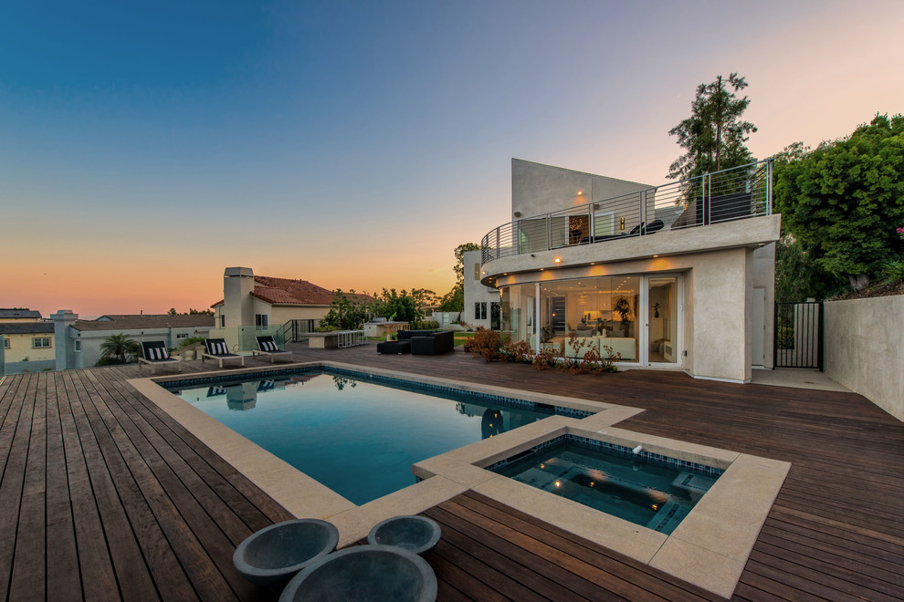 This is an example of a large modern backyard rectangular lap pool in Los Angeles with a hot tub and decking.