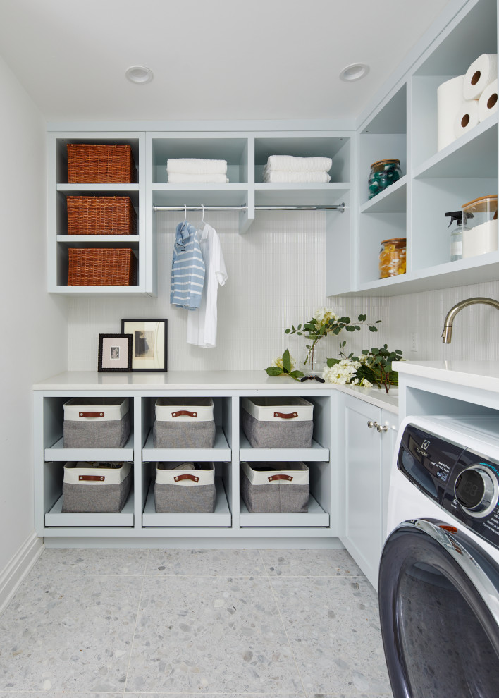 Design ideas for a country l-shaped laundry room in New York with an undermount sink, open cabinets, grey cabinets, white walls, a side-by-side washer and dryer, grey floor and white benchtop.