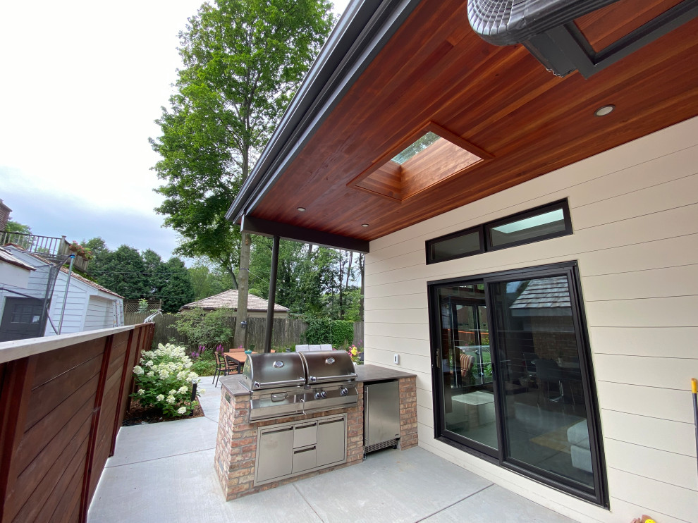 Foto di un patio o portico moderno di medie dimensioni e dietro casa con lastre di cemento e un tetto a sbalzo