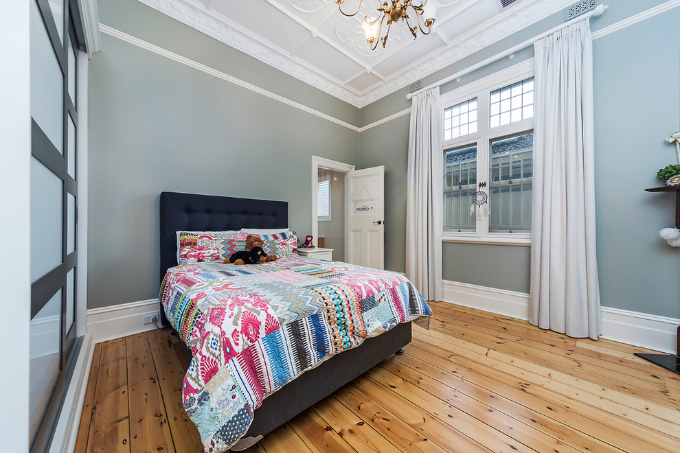 This is an example of a transitional bedroom in Adelaide with blue walls, light hardwood floors and no fireplace.