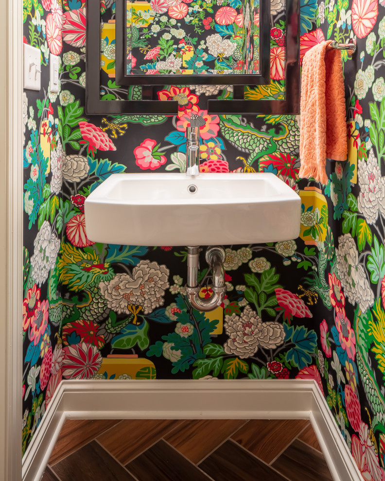 This is an example of a transitional powder room in Minneapolis with multi-coloured walls, wood-look tile, a wall-mount sink, brown floor and wallpaper.