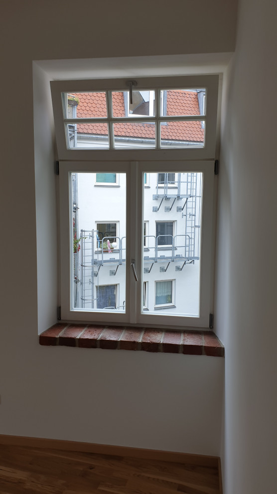 Mittelgroße Mediterrane Wohnküche mit weißer Wandfarbe, Laminat, braunem Boden und Ziegelwänden in München