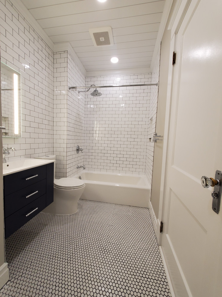 This is an example of a small transitional master bathroom in Cincinnati with flat-panel cabinets, blue cabinets, an alcove tub, a shower/bathtub combo, a two-piece toilet, white tile, ceramic tile, grey walls, porcelain floors, an integrated sink, engineered quartz benchtops, white floor, a shower curtain, white benchtops, a niche, a single vanity, a floating vanity and timber.
