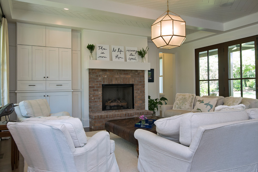 This is an example of a mid-sized country formal open concept living room in Raleigh with white walls, dark hardwood floors, a standard fireplace, a brick fireplace surround, no tv and brown floor.