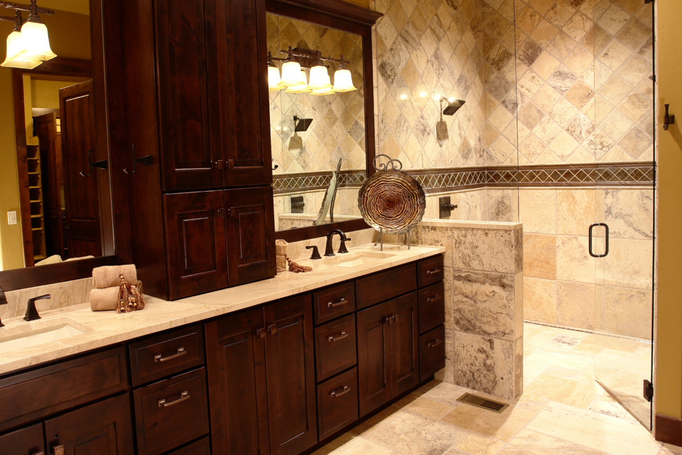 Photo of a mid-sized country master bathroom in Denver with an undermount sink, raised-panel cabinets, dark wood cabinets, a curbless shower, beige tile, stone tile, beige walls, travertine floors, granite benchtops, beige floor and a hinged shower door.