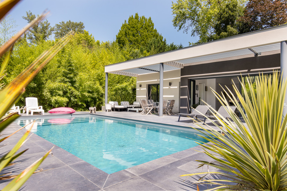 Mid-sized contemporary rectangular pool in Toulouse with tile.
