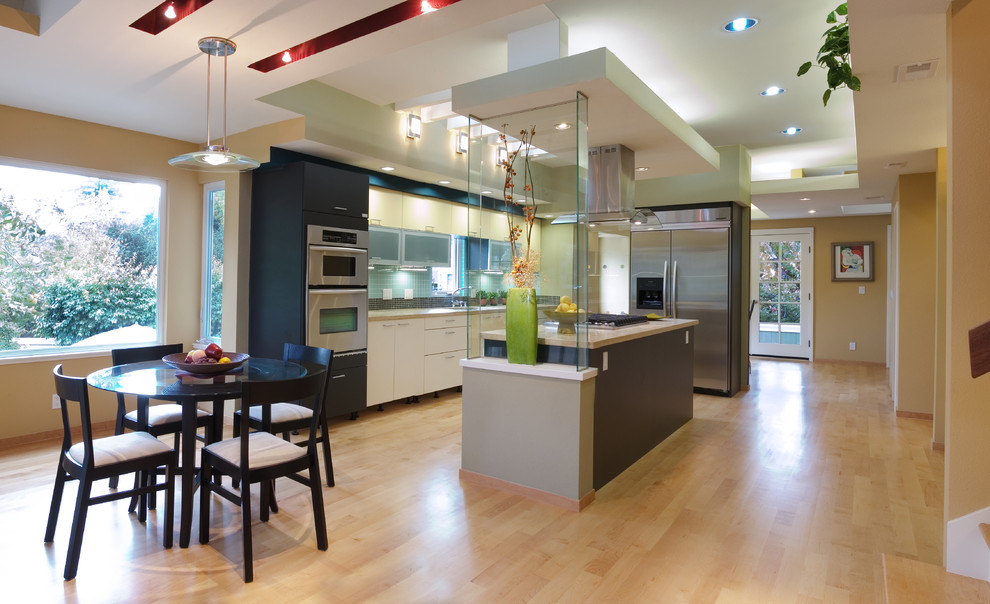 Inspiration for a mid-sized modern l-shaped open plan kitchen in San Francisco with an undermount sink, flat-panel cabinets, yellow cabinets, limestone benchtops, glass tile splashback, stainless steel appliances, medium hardwood floors, with island and brown floor.