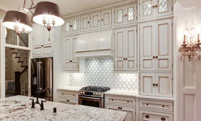 Example of a mid-sized classic l-shaped open concept kitchen design in San Francisco with a farmhouse sink, recessed-panel cabinets, white cabinets, granite countertops, white backsplash, porcelain backsplash, stainless steel appliances and an island