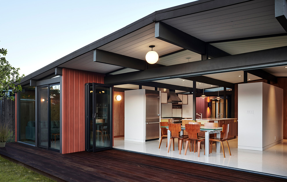 This is an example of a small midcentury backyard deck in San Francisco with a roof extension.