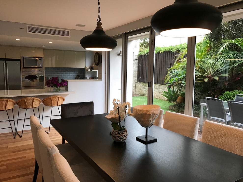 This is an example of a mid-sized contemporary open plan dining in Sydney with white walls, light hardwood floors and no fireplace.