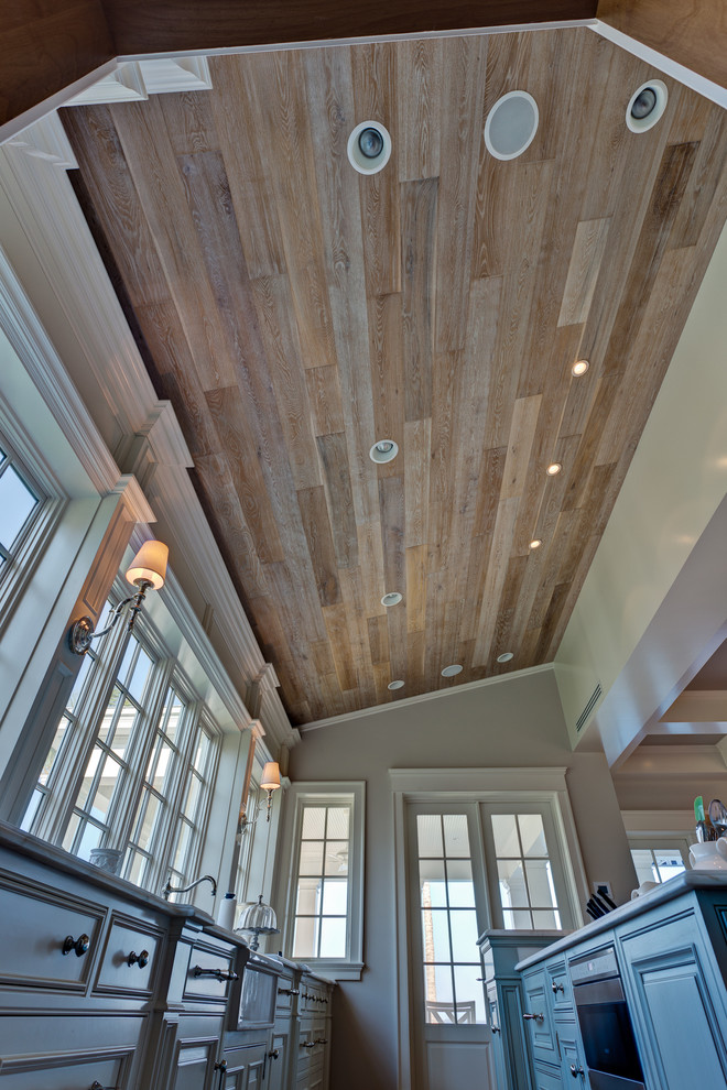 Large transitional l-shaped medium tone wood floor and brown floor eat-in kitchen photo in Miami with a farmhouse sink, raised-panel cabinets, blue cabinets, quartzite countertops, white backsplash, subway tile backsplash, stainless steel appliances and an island
