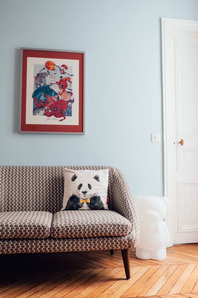This is an example of a mid-sized contemporary nursery for boys in Paris with blue walls and light hardwood floors.