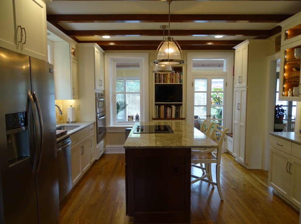 Eat-in kitchen - mid-sized transitional u-shaped medium tone wood floor eat-in kitchen idea with an undermount sink, shaker cabinets, white cabinets, granite countertops, beige backsplash, ceramic backsplash, stainless steel appliances and an island