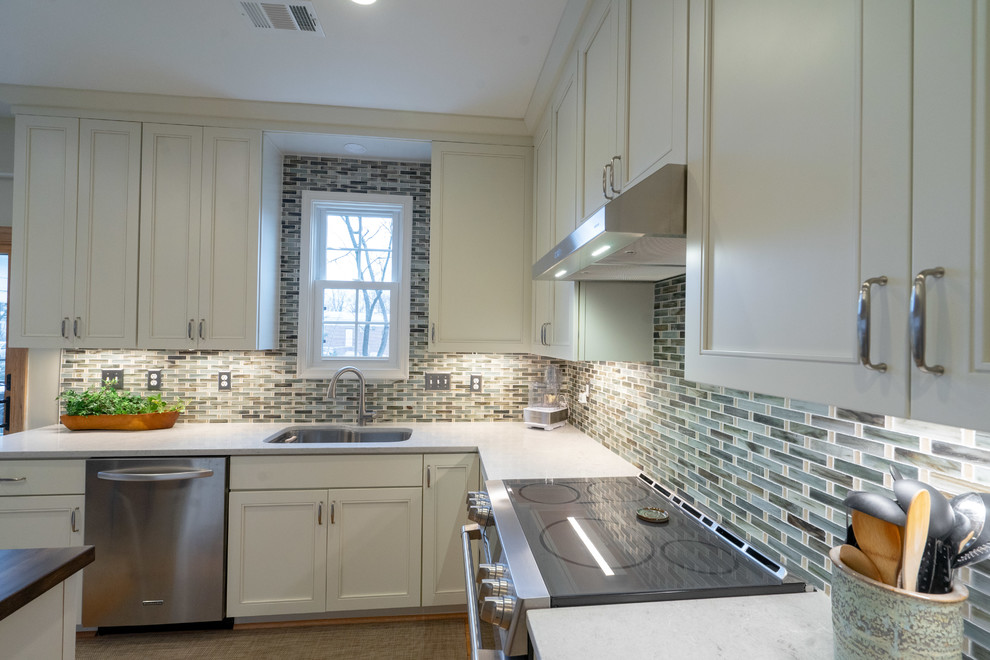 This is an example of a traditional u-shaped eat-in kitchen in DC Metro with an undermount sink, flat-panel cabinets, white cabinets, quartzite benchtops, multi-coloured splashback, ceramic splashback, stainless steel appliances, light hardwood floors, with island, yellow floor and white benchtop.