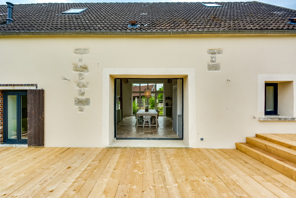 Idée de décoration pour une grande façade de maison beige bohème en brique à un étage avec un toit en tuile.
