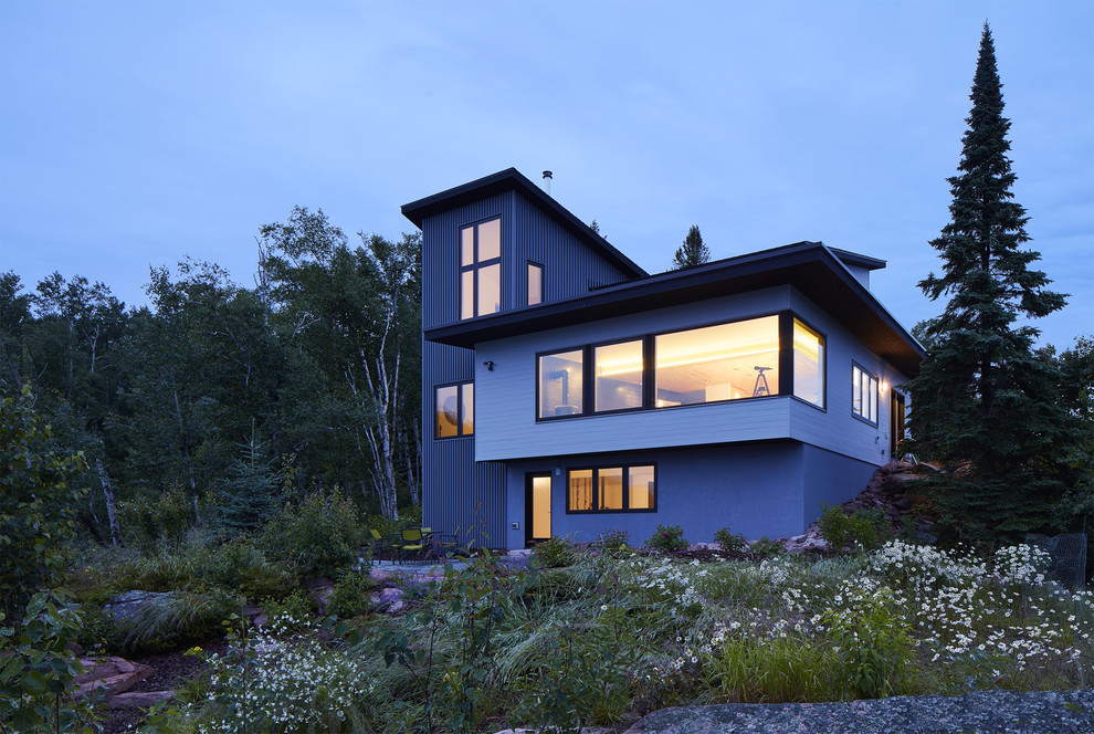 This is an example of a beach style three-storey house exterior in Minneapolis with metal siding, a shed roof and a metal roof.